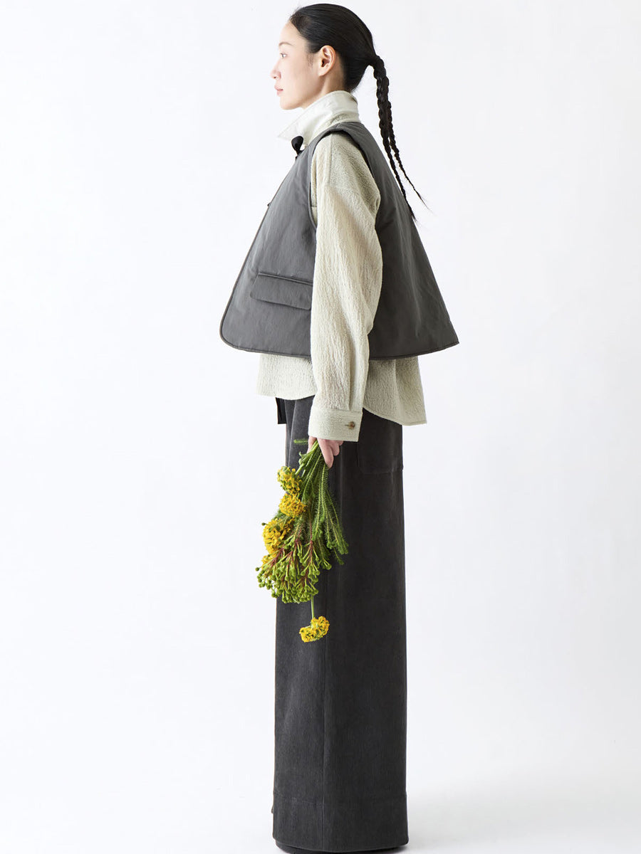 Soh side styling view of dark grey padded gilet over a cream shirt