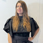 Front view of the Igor Dobranic May black bolero showing its cropped body and folded shoulder panels