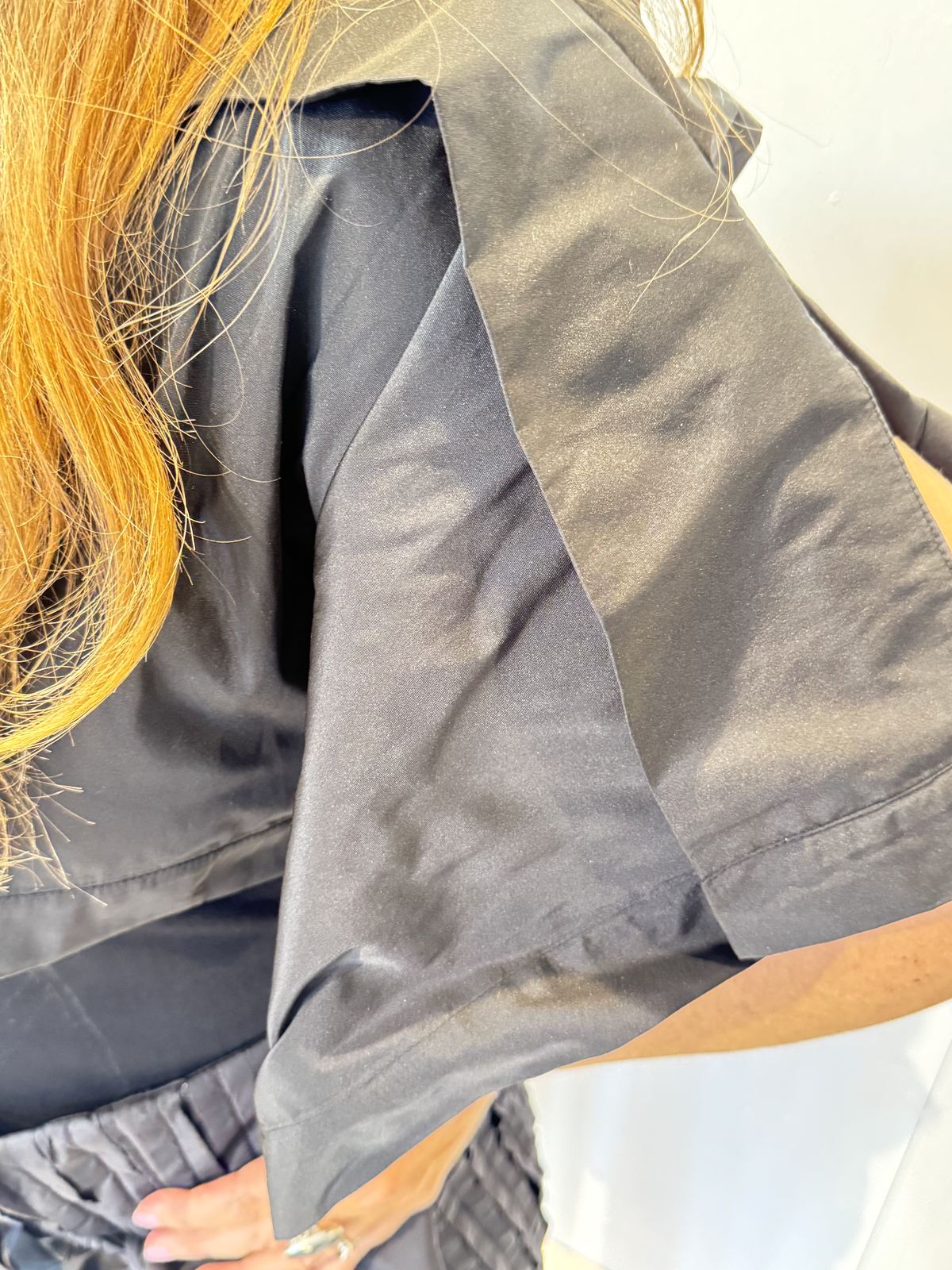 Close-up of the May bolero showing its smooth black fabric and folded shoulder panel