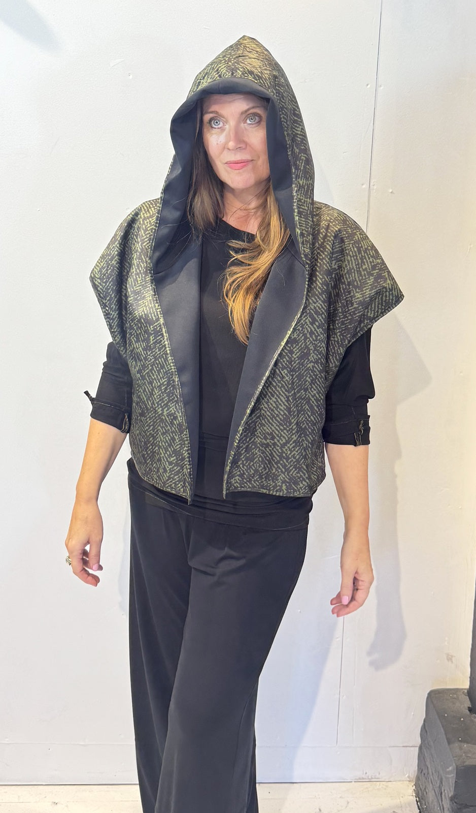 Front view of the Pensy waistcoat with its green patterned side outward and hood raised
