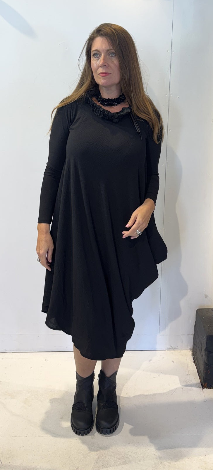 Front view of the Igor Dobranic Strelizia black dress showing its draped asymmetric hem
