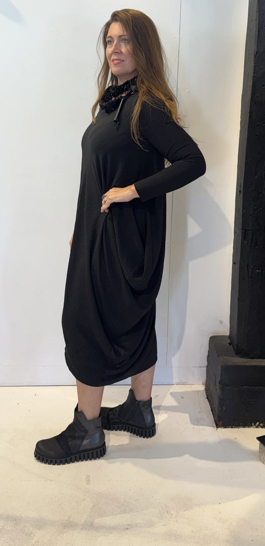 Side view of the Strelizia black dress showing the fabric gathered into soft folds