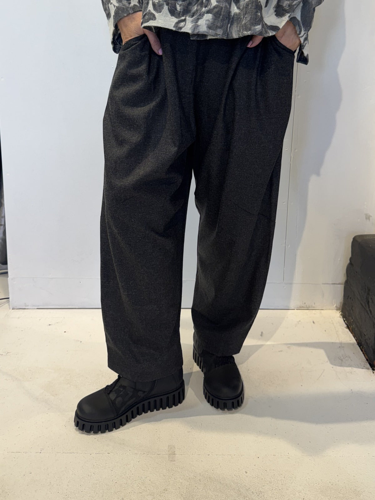 Front view of the Igor Dobranic Ivy dark grey trousers showing their rounded legs and side pockets