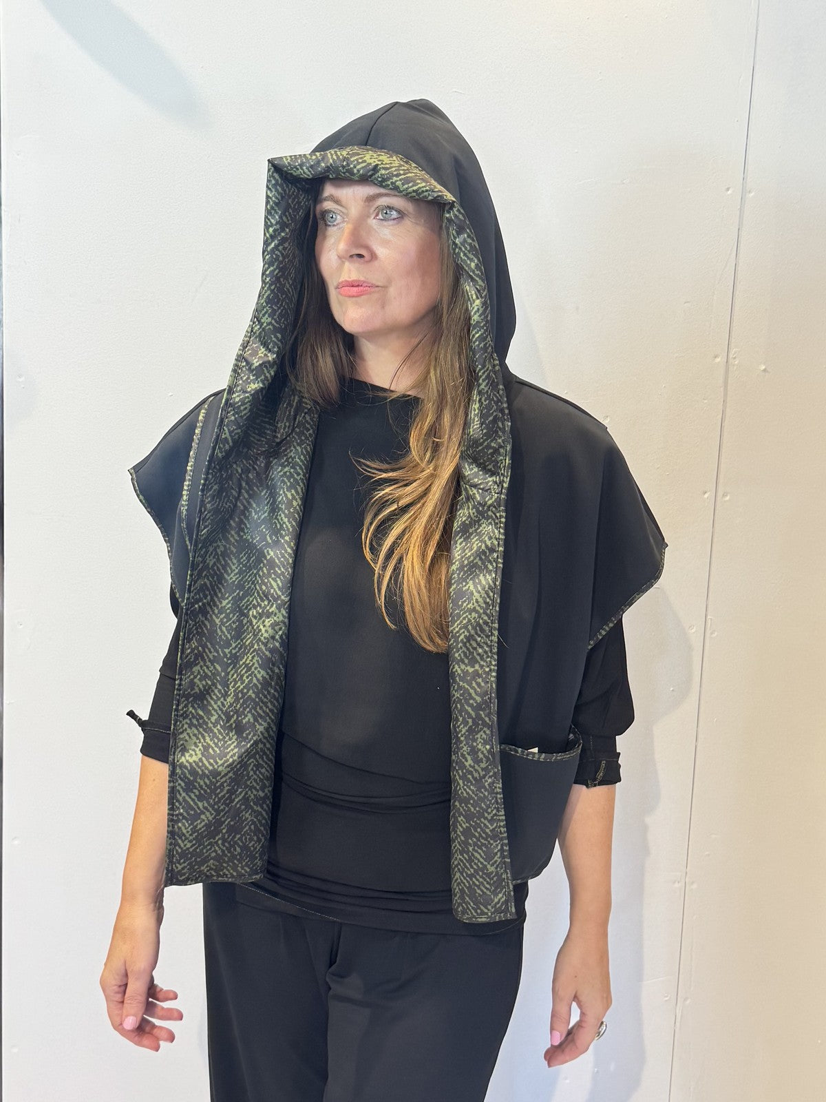 Front view of the Pensy waistcoat on its plain black side with the hood raised