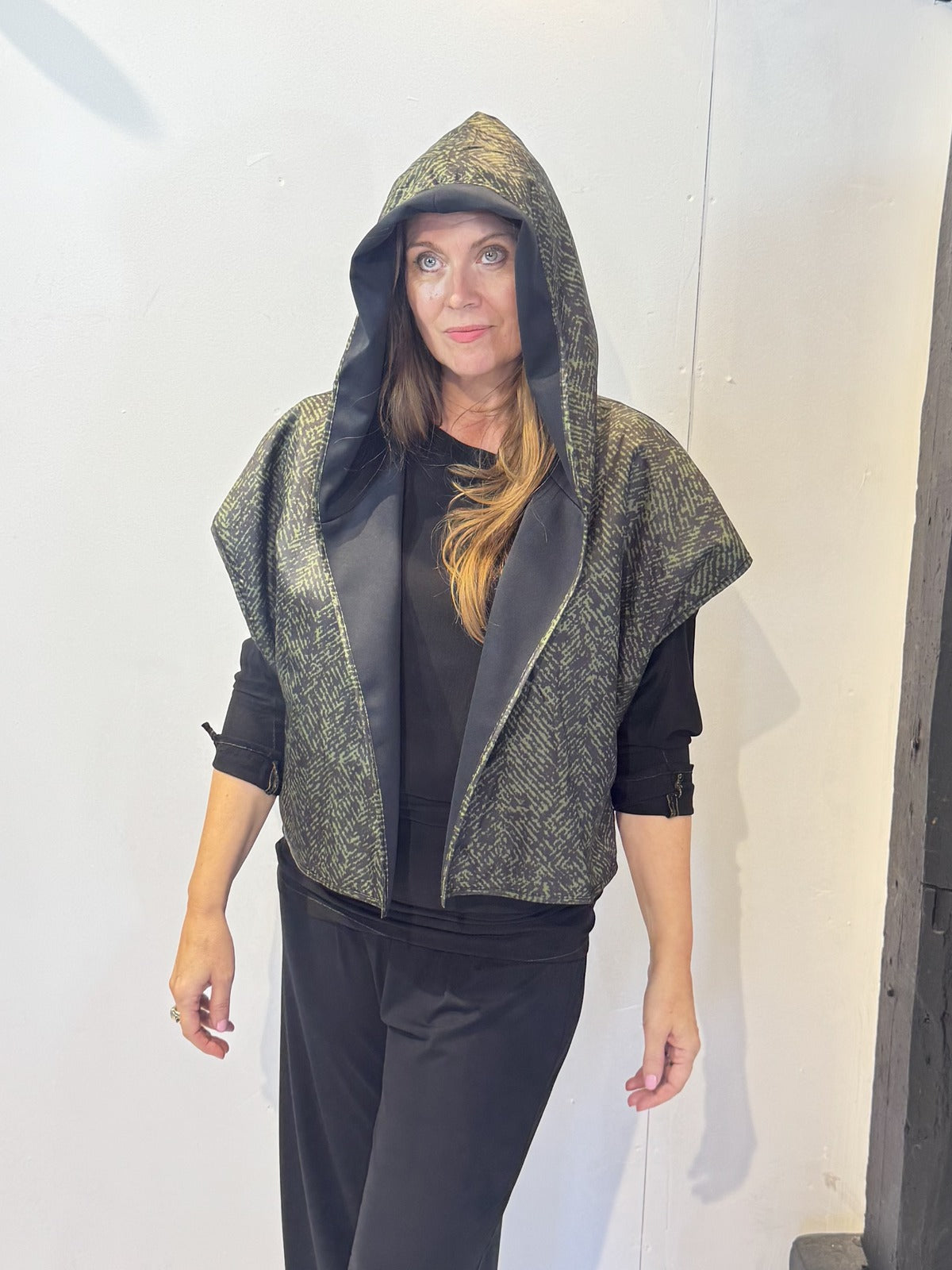 Front view of the Pensy waistcoat with its green patterned side outward and hood raised