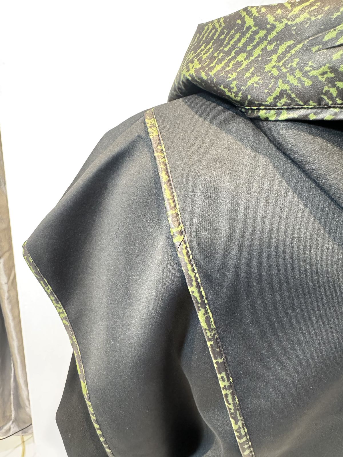 Close-up of the Pensy waistcoat showing its plain black fabric and green patterned seam edging