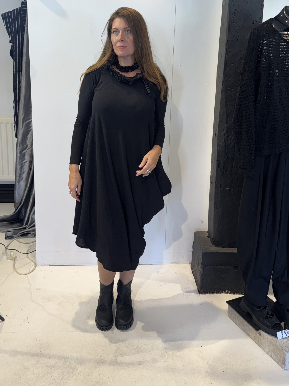 Front view of the Igor Dobranic Strelizia black dress showing its draped asymmetric hem