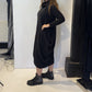 Side view of the Strelizia black dress showing the fabric gathered into soft folds