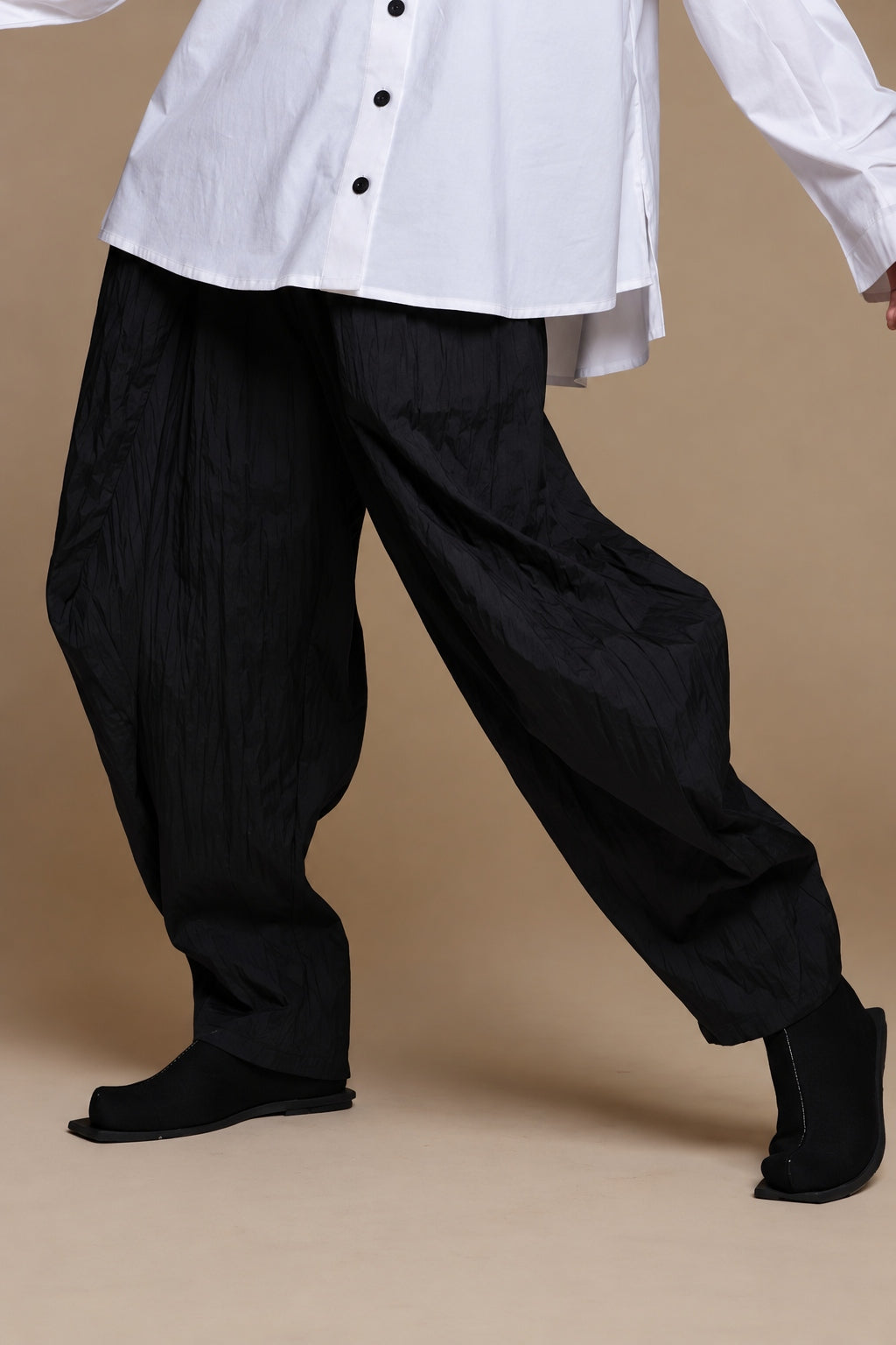 Black crinkle balloon trousers, movement view showing the rounded legs