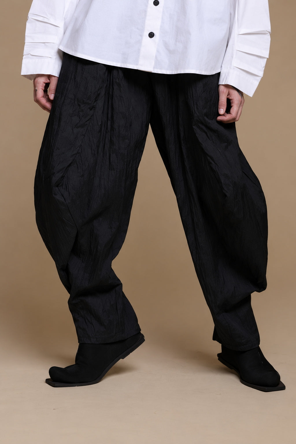 Black crinkle balloon trousers, detail of the textured legs and tapered hems