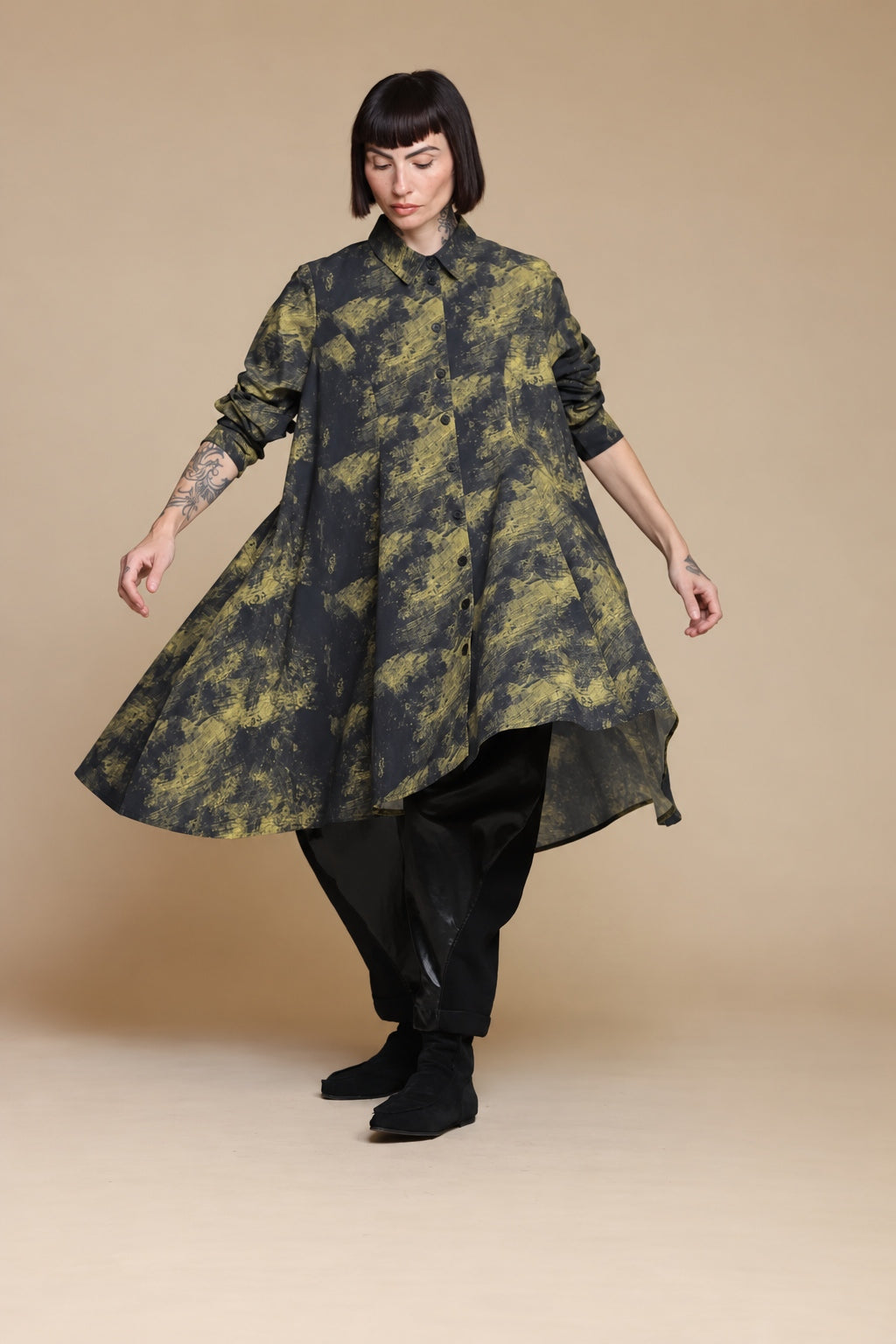 Yellow-olive and charcoal linen shirt in motion, showing the wide flowing hem