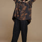 Copper-brown and charcoal shirt, relaxed pose with arms behind the model's head