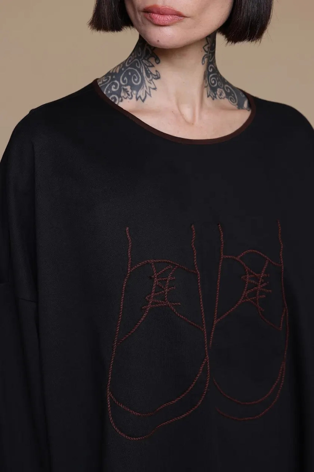 Black top, close-up of the neckline and shoe artwork