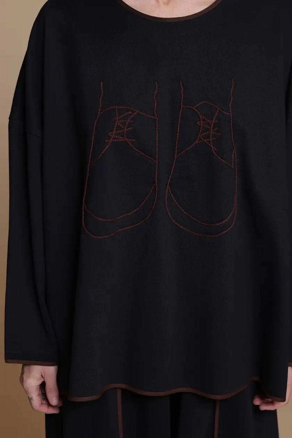 Black top, detail of the shoe artwork and contrast-trimmed hem