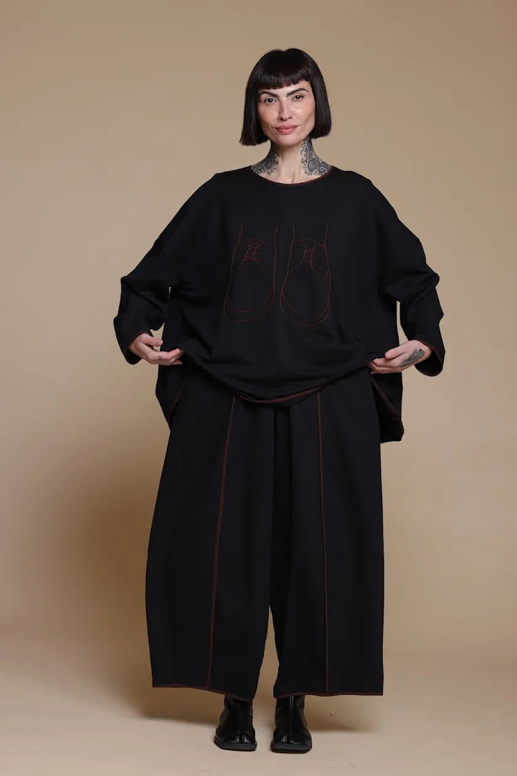 Black shoe-artwork top, front view with the hem held out to show its width