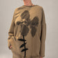 Kedziorek taupe floral print top with black ribbon leaf detail and exposed seams, front view