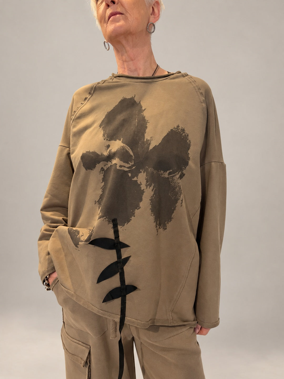 Kedziorek taupe floral print top with black ribbon leaf detail and exposed seams, front view