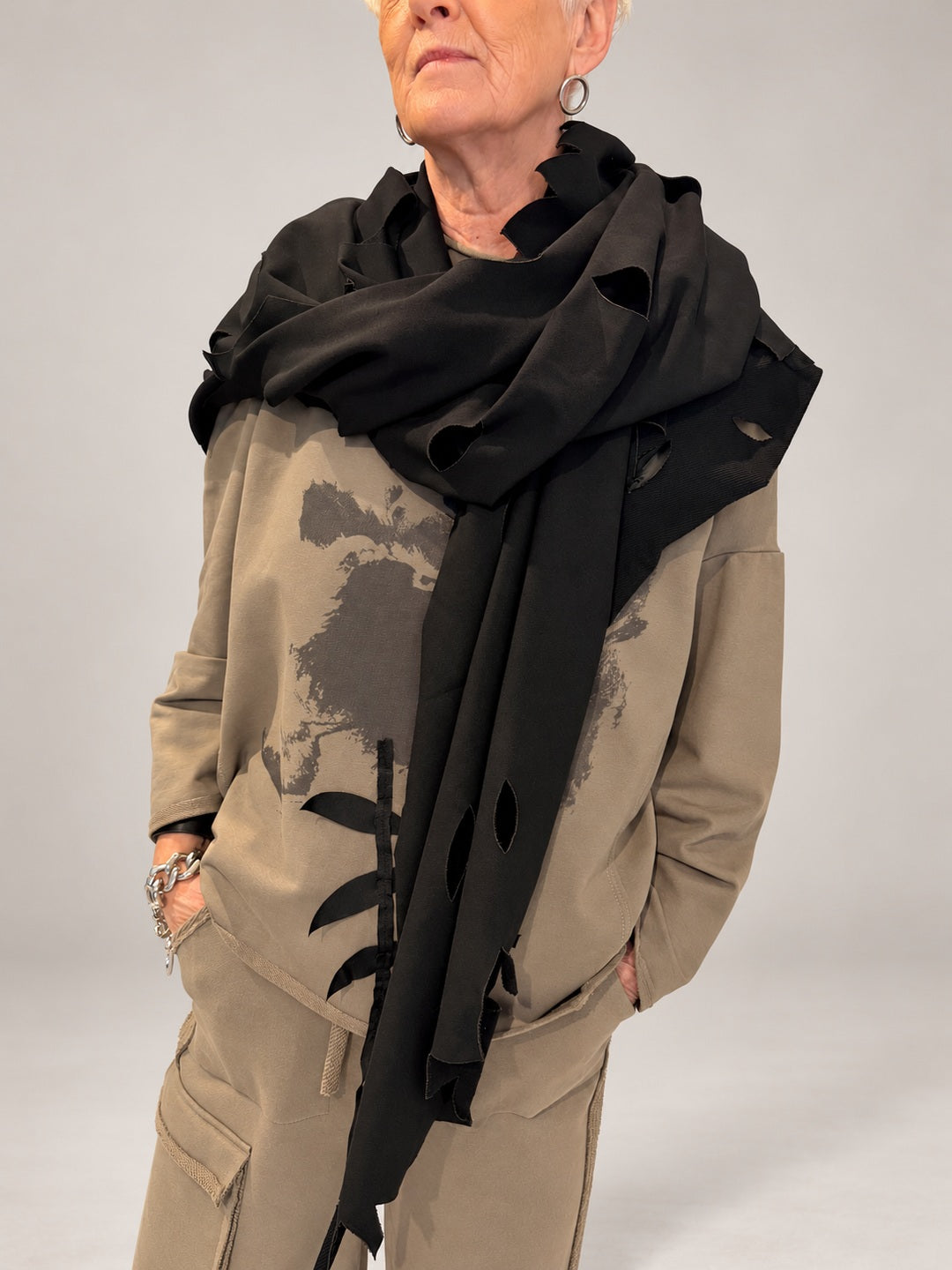 Kedziorek black cut-out scarf draped around the shoulders over a taupe printed top, front view
