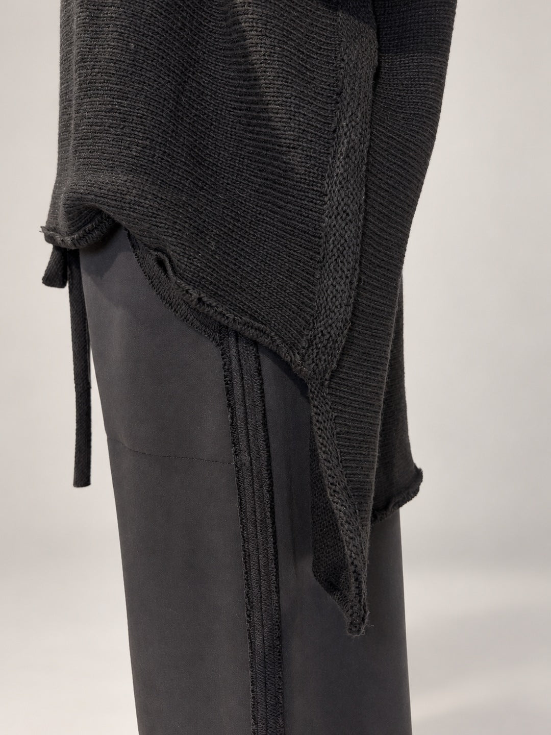 Kedziorek black merino wool top, close-up of stepped hem, side opening and raw-edge knit texture